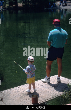 Ein Vater und ein kleinen Sohn Fische in einem Teich an einem Sommertag Urlaub Stockfoto