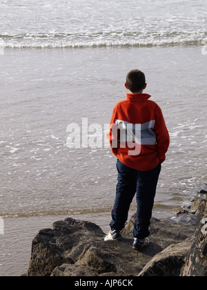 Teenager stehen auf Felsen mit Blick auf das Meer Stockfoto