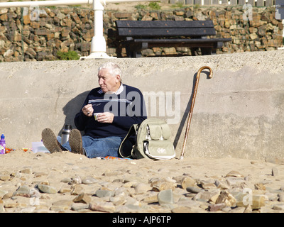 Mann mit grauen Haaren, am Strand sitzen Stockfoto