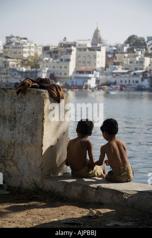 Jungen Jungen sitzen am Rande des Lake Pichola, Udaipur, Rajasthan, Indien Stockfoto