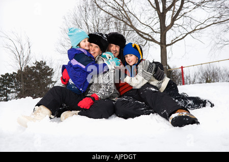 Porträt des kaukasischen Familienglück von vier sitzen im Schnee lächelnd an veiwer Stockfoto