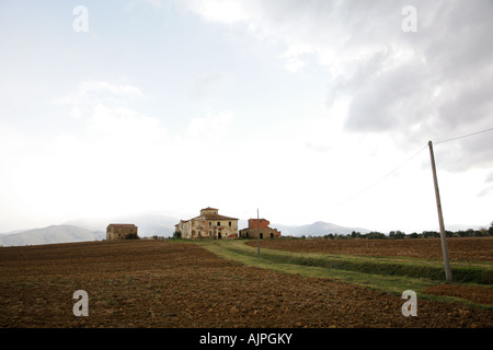 Ansicht der alten und verlassenen Bauernhaus in der toskanischen Landschaft. Die Stadt Cortona ist auf dem rechten Hügel im Hintergrund sichtbar. Stockfoto