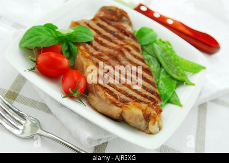 Gegrilltes Rindersteak New York serviert auf einem Teller mit Gemüse Stockfoto