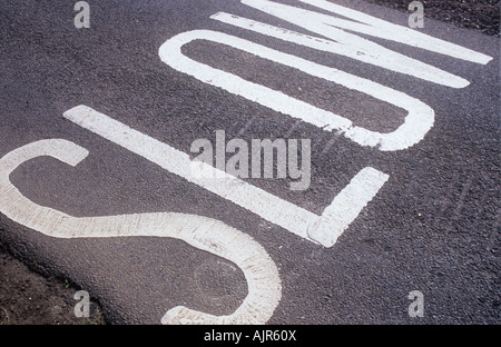 Schmale graue Asphaltstraße mit SLOW gemalt über seine gesamte Breite Stockfoto