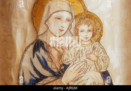 Detail der gestickten Bild der Jungfrau Maria Holding Baby Jesus Christus in gedeckten Farben auf Beige Stoff Stockfoto