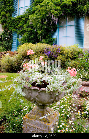 Stone Pott ist bei Broadleas Garten, Devizes, Wiltshire mit blauen Fensterläden des Hauses im Hintergrund. Stockfoto