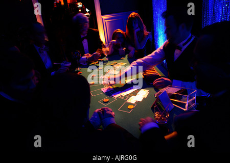 Black-Jack-Tisch mit Spielern in der Silhouette. Sehr launisch, dunkle Seite des Spiels. Karten, Chips in spot-Licht mit Händler. Menschen gefundenes Fressen, dramatische Foto Stockfoto