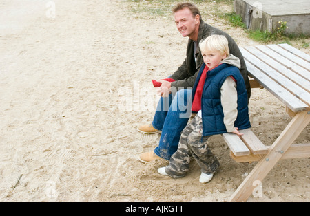 Ein Vater mit seinem Sohn sitzen auf einer Bank ausruhen. Stockfoto