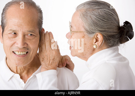 Nahaufnahme einer älteren Frau Flüstern zu einem älteren Mann Stockfoto