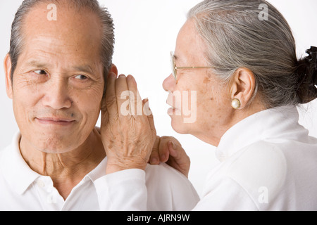 Nahaufnahme einer älteren Frau Flüstern zu einem älteren Mann Stockfoto