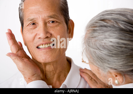 Nahaufnahme einer älteren Frau Gesicht eines älteren Mannes in ihren Händen hält Stockfoto