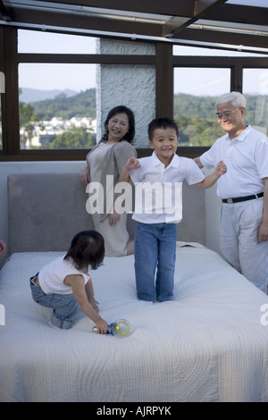 Großeltern Blick auf ihre Enkel und Enkelin spielen auf dem Bett Stockfoto