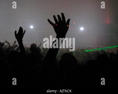 Partygänger Welle ihre Hände in der Luft als Laser-Licht-Stream quer durch den Raum auf einer Rave Dance-Party. Stockfoto