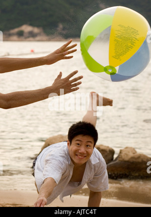 Zwei junge Männer am Strand mit einem Wasserball spielen Stockfoto
