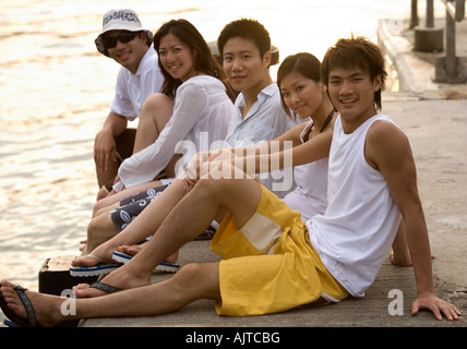 Porträt von zwei jungen Frauen und drei junge Männer sitzen auf einem pier Stockfoto