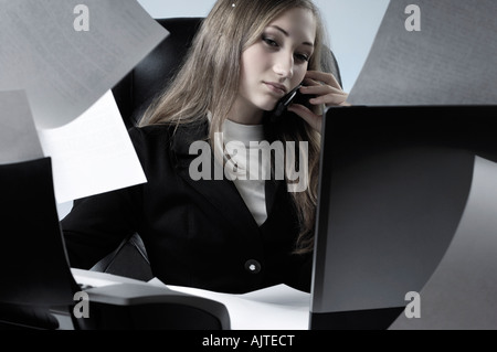 Junge Geschäftsfrau arbeiten im Büro mit Papier fliegen überall reden über ein Handy Stockfoto