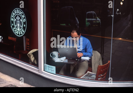 Drahtlose mobile Mitarbeiter: Man arbeitet intensiv an einem Laptopcomputer im Fenster ein Coffee-Shop, City of London, England Stockfoto