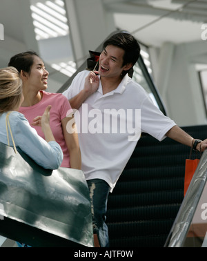 Seitenansicht einer jungen Frau im Gespräch mit einem jungen Paar in einer Shopping mall Stockfoto