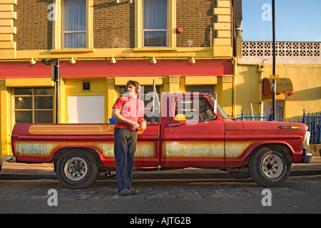 Überlebende von roten Ford F100 Pickup-Truck mit einem leuchtend roten und gelben Gebäude im Hintergrund Stockfoto