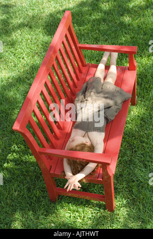 Kleines Mädchen auf rote Bank im Schatten, grünen Rasen in voller Länge, Hintergrund, erhöhte Ansicht liegend Stockfoto