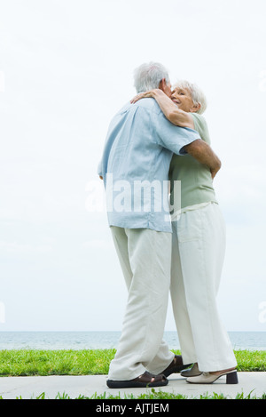 Älteres paar tanzen auf Bürgersteig mit Blick auf Meer, in voller Länge Stockfoto