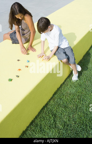 Mutter und Sohn sitzen im Freien, spielen mit Kunststoff Tierfiguren, erhöhte Ansicht, in voller Länge Stockfoto