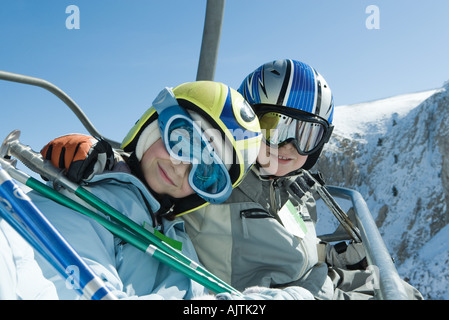 Zwei junge Skifahrer am Sessellift, zusammen in die Kamera Lächeln, Porträt Stockfoto