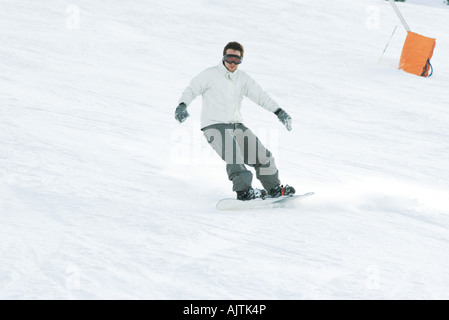 Junger Mann Snowboarden auf der Piste, in voller Länge Stockfoto