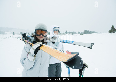 Zwei junge Skifahrer zusammen spazieren, Blick mit Skiern auf den Schultern, einen in die Kamera Stockfoto