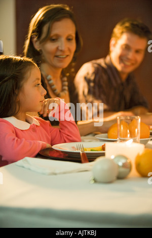 Mädchen sitzen am Tisch mit Familie, wegschauen Stockfoto