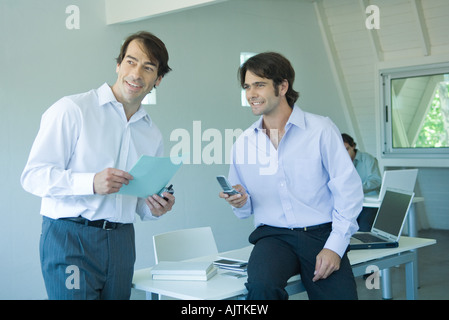 Zwei Geschäftsleute in Büro, eine Holding-Handy Stockfoto