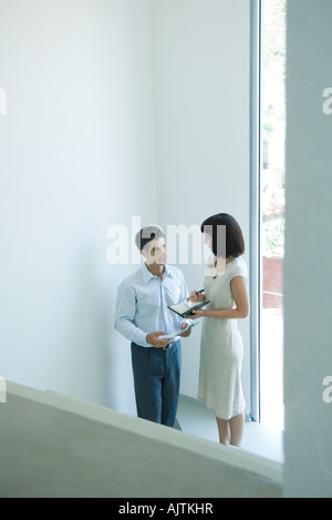 Reife Geschäftsmann im Gespräch mit jungen Kollegin in der Nähe von Fenster, erhöhte Ansicht Stockfoto