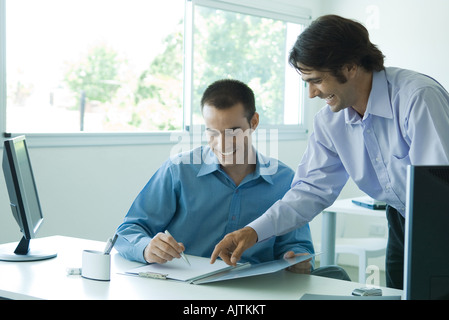 Zwei junge Unternehmer mit Blick auf Dokument zusammen, lachen Stockfoto