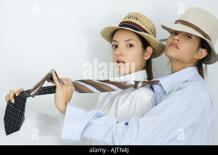 Zwei junge Freundinnen gekleidet in Mützen und Krawatten, einer hinter dem anderen Blick in die Kamera Stockfoto