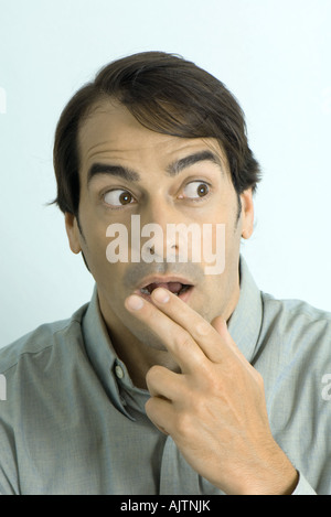 Mann hält Finger vor den Mund, auf der Suche überrascht, portrait Stockfoto