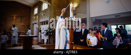 Erste Kommunion Priester Beleuchtung Paschal Kerze Bernhardiner s Kirche Sussex England Stockfoto