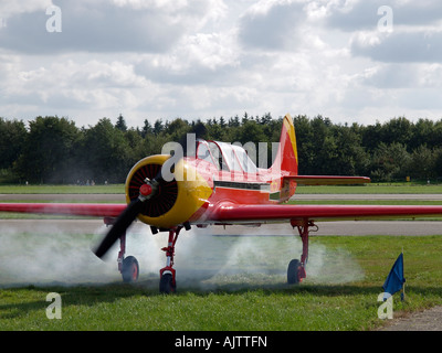 Starten classic Jakowlew Yak 52 Flugzeug in eine Wolke von Rauch, die angeblich ist normal seppe Flugplatz die Niederlande Stockfoto