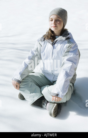 Teenager-Mädchen indischen Stil auf Schnee sitzend, mit geschlossenen Augen und Kopf nach hinten, in voller Länge Stockfoto