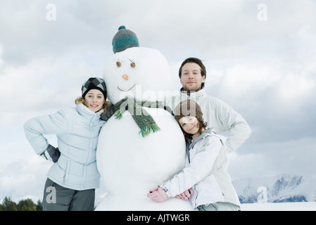 Junge Freunde posiert neben Schneemann, Porträt Stockfoto