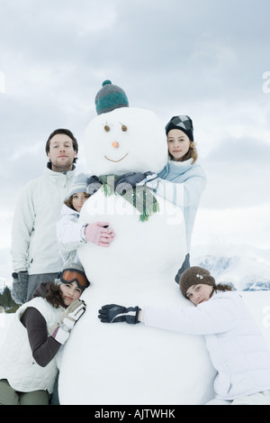 Junge Freunde gruppieren sich um Schneemann, posieren, portrait Stockfoto