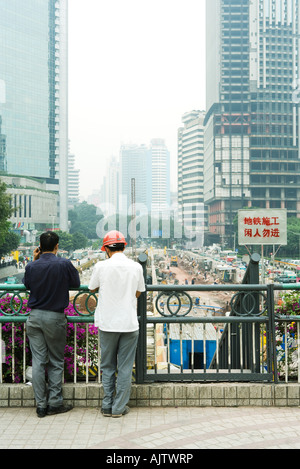 China, Provinz Guangdong, Guangzhou, zwei Männer, die mit Blick auf Baustelle, Rückansicht Stockfoto