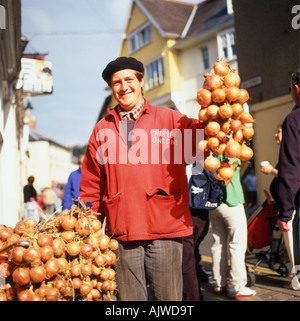 Ein lächelndes französische Zwiebel Verkäufer mit einem Fahrrad und Baskenmütze holding String der Zwiebeln verkauft er auf einer Straße in Brecon, Powys Wales UK KATHY DEWITT Stockfoto