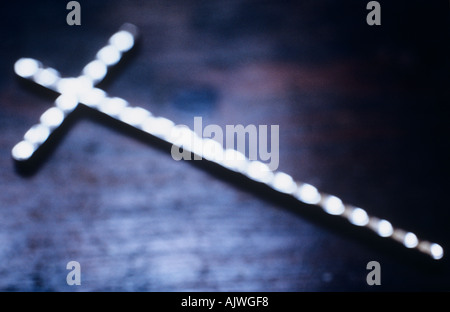 Impressionistische Silber Bejeweled Kruzifix auf einer strukturierten blau braun Holzoberfläche liegend Stockfoto