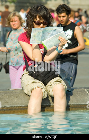 Vertikale Nahaufnahme Portrait einer japanischen Dame ihre Füße am Trafalgar Square Kühlung, während eine Uderground-Karte lesen. Stockfoto