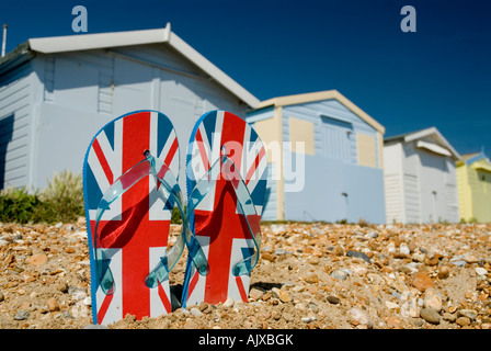 Paar Flip flops auf Kiesstrand mit Strandhütten im Hintergrund St Leonards am Meer Hastings Sussex England GB Stockfoto