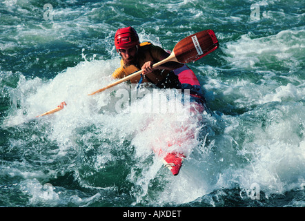 Junger Mann paddeln Kanu in abgehackt Flusswasser. Stockfoto