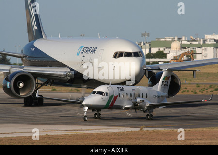 Flugverkehr. Das Flugzeug steht am Flughafen Lissabon in der Schlange. Ein PGA Beech 1900D steht auf der Landebahn, während ein Star Air Boeing 767 Jet an der Reihe ist. Stockfoto