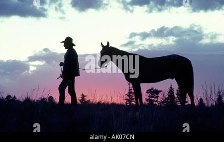 Eine amerikanische Cowboy auf eine große Rinderfarm im südlichen Colorado bereitet sich mit seinem Pferd bei Sonnenaufgang für einen langen Tag Stockfoto