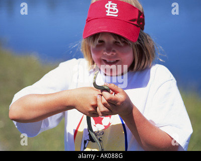 Ein junges Mädchen untersucht eine kleine Wasserschlange entlang der Deschutes River Trail während einer Sommerwanderung Stockfoto