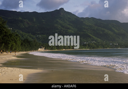 Wenig Sonnenlicht auf dem glatten, sandigen Strand von Beau Vallon und den bewaldeten Bergen auf der Insel Mahe, den Seychellen. Stockfoto